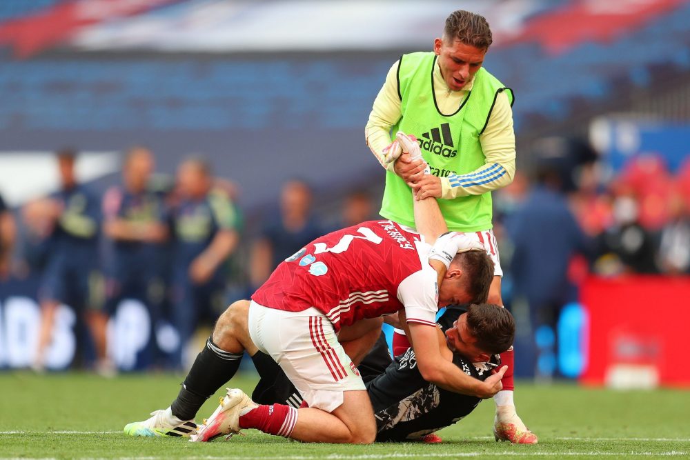 Arsenal's Argentinian goalkeeper Emiliano Martinez is mobbed by Arsenal's Scottish defender Kieran Tierney (L) after the English FA Cup final footb...