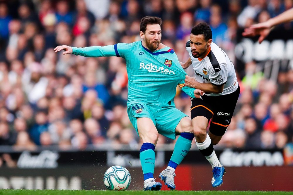 VALENCIA, SPAIN - JANUARY 25: Lionel Messi of FC Barcelona is tackled by Francis Coquelin of Valencia CF during the Liga match between Valencia CF ...