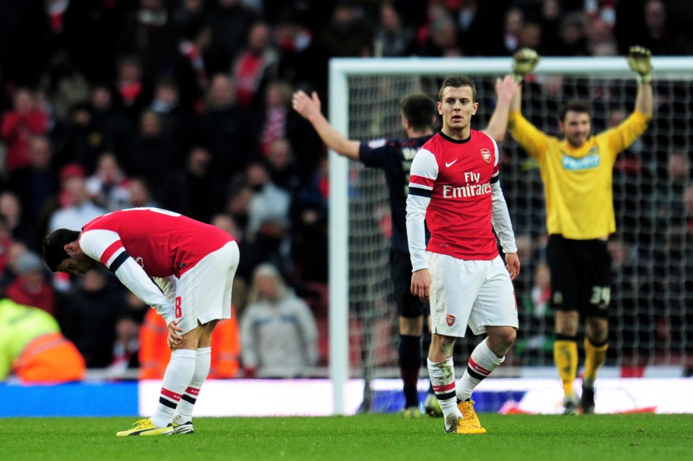LONDON, ENGLAND - FEBRUARY 16: Dejected Arsenal players Mikel Arteta (L) and Jack Wilshere (R) look on as Blackburn players celebrate their team's 1-0 victory during the FA Cup with Budweiser fifth round match between Arsenal and Blackburn Rovers at Emirates Stadium on February 16, 2013 in London, England. (Photo by Shaun Botterill/Getty Images)