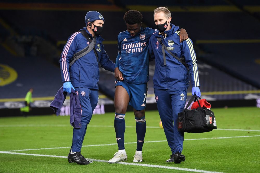 Arsenal's English striker Bukayo Saka (C) is helped off the pitch with an injury during the English Premier League football match between Leeds Uni...
