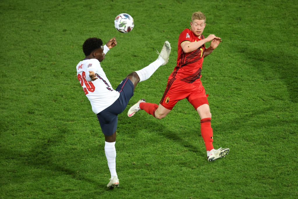 England's midfielder Bukayo Saka (L) and Belgium's Kevin De Bruyne fight for the ball during the UEFA Nations League football match between Belgium and England, on November 15, 2020 at Den Dreef stadium in Louvain. (Photo by VIRGINIE LEFOUR/BELGA/AFP via Getty Images)
