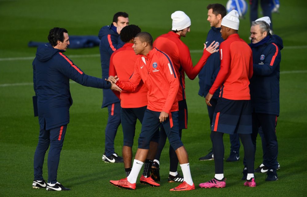 Paris Saint-Germain's French forward Kylian MBappe (C) shakes hands of Paris Saint-Germain's Spanish head coach Unai Emery during a training sessio...