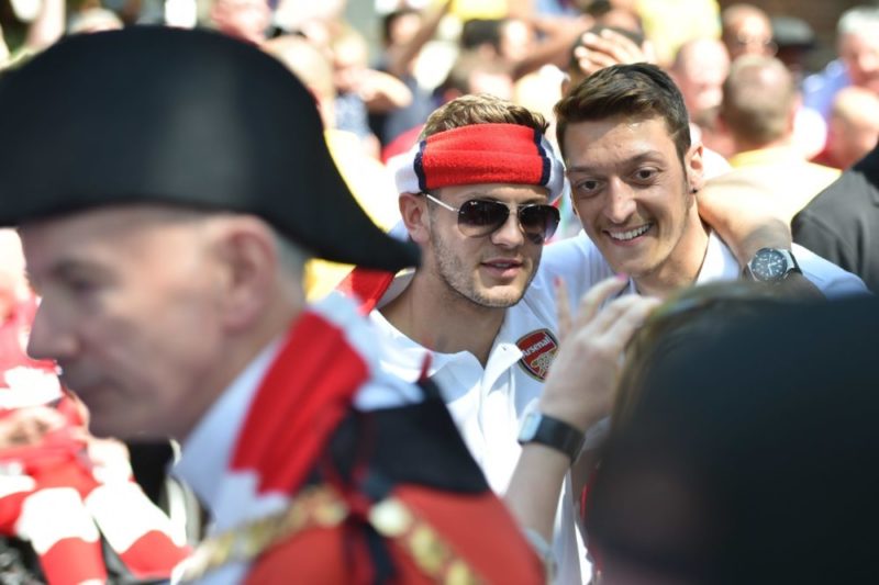 Arsenal's English midfielder Jack Wilshere (C) and Arsenal's German midfielder Mesut Ozil pose for photographs during their victory parade in London on May 18, 2014, following their win in the English FA Cup final football match on May 17, 2014 against Hull City. Aaron Ramsey insists Arsenal's dramatic FA Cup final victory will be the springboard for more glory now the Gunners have finally ended their trophy drought. Ramsey scored the extra-time goal that clinched a 3-2 win over Hull in Saturday's clash at Wembley, putting silverware back in the Arsenal trophy cabinet for the first time since 2005. AFP PHOTO / LEON NEAL 