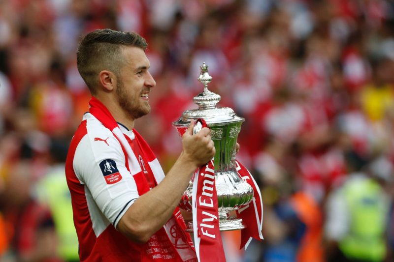 Arsenal's Welsh midfielder Aaron Ramsey holds the FA Cup trophy as Arsenal players celebrate their victory over Chelsea on the pitch after the Engl...