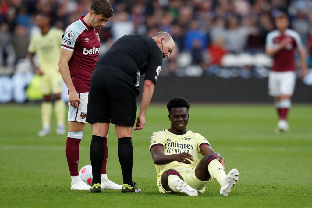 Arsenal's English midfielder Bukayo Saka reacts on the pitch after being tackled during the English Premier League football match between West Ham United and Arsenal at the London Stadium, in London on May 1, 2022. (Photo by IAN KINGTON/IKIMAGES/AFP via Getty Images)