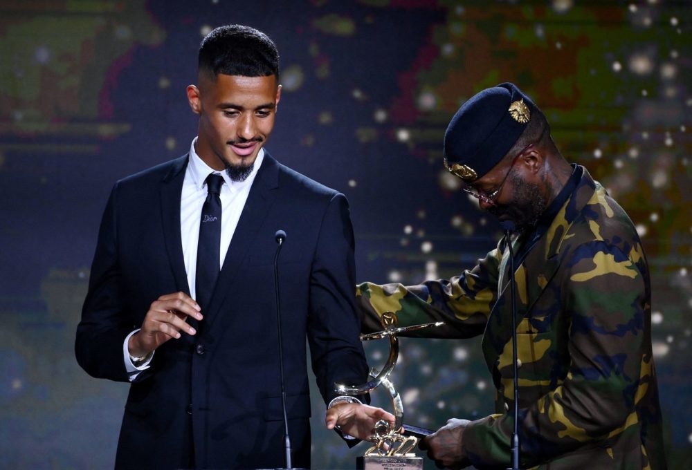 Marseille's French defender William Saliba (L) delivers a speech after receiving the best hope player trophy from French former player Djibril Ciss...