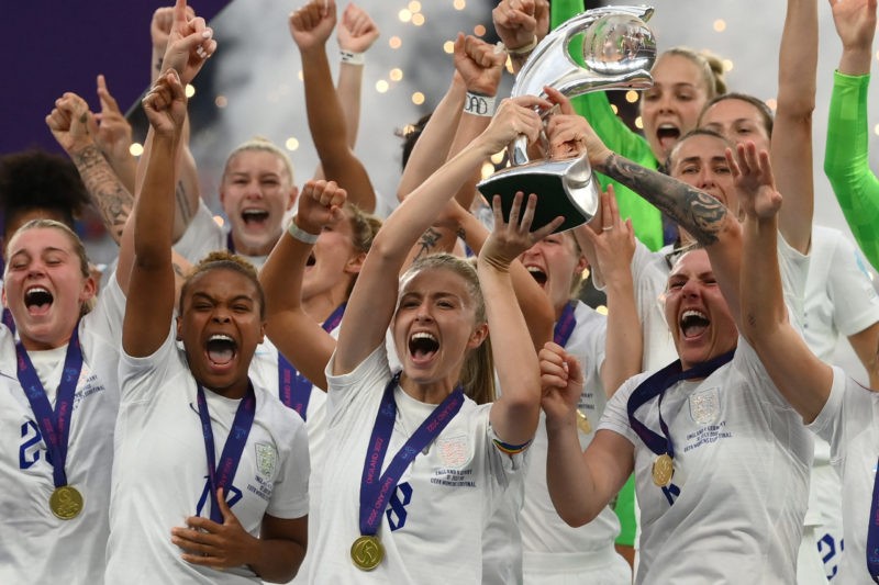 TOPSHOT - England's midfielder Leah Williamson (C) and England's defender Millie Bright (R) lift the trophy as England's players celebrate after th...