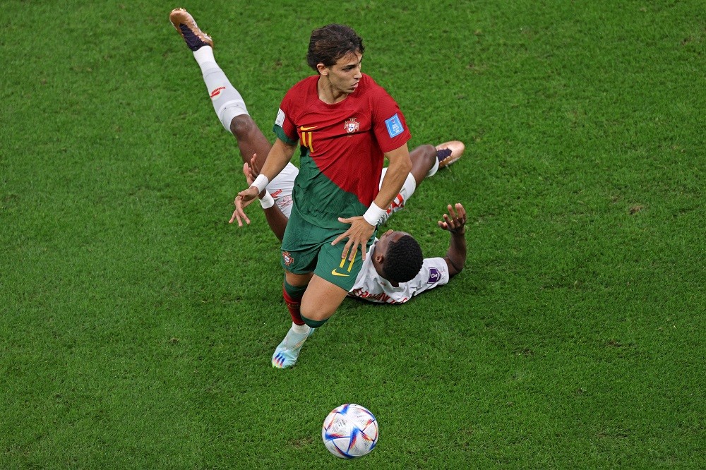 Portugal forward Joao Felix runs past Switzerland midfielder Edimilson Fernandes (back) during the Qatar 2022 World Cup round of 16 football match ...