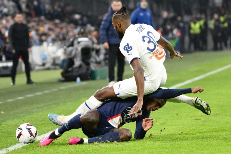 TOPSHOT - Paris Saint-Germain's Portuguese defender Nuno Mendes and Marseille's Portuguese defender Nuno Tavares (top) fall during the French L1 football match between Olympique Marseille (OM) and Paris Saint-Germain (PSG) at the Velodrome stadium in Marseille, southern France on February 26, 2023.  (Photo by CHRISTOPHE SIMON/AFP via Getty Images)