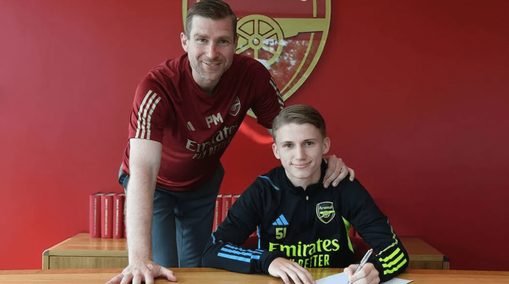 Jimi Gower signing his first professional contract with Arsenal, alongside Per Mertesacker (Photo via Arsenal.com)