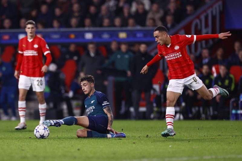 Arsenal's Polish defender #15 Jakub Kiwior (C) lies on the pitch as he fights for the ball with PSV Eindhoven's US defender #08 Sergino Dest during a UEFA Champions League group B football match between PSV Eindhoven and Arsenal FC at the Philips Stadium in Eindhoven, on December 12, 2023. (Photo by KENZO TRIBOUILLARD/AFP via Getty Images)