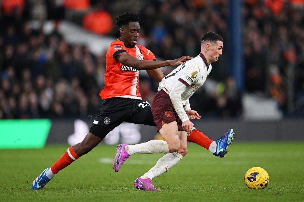 LUTON, ENGLAND: Phil Foden of Manchester City is challenged by Albert Sambi Lokonga of Luton Town during the Premier League match between Luton Tow...