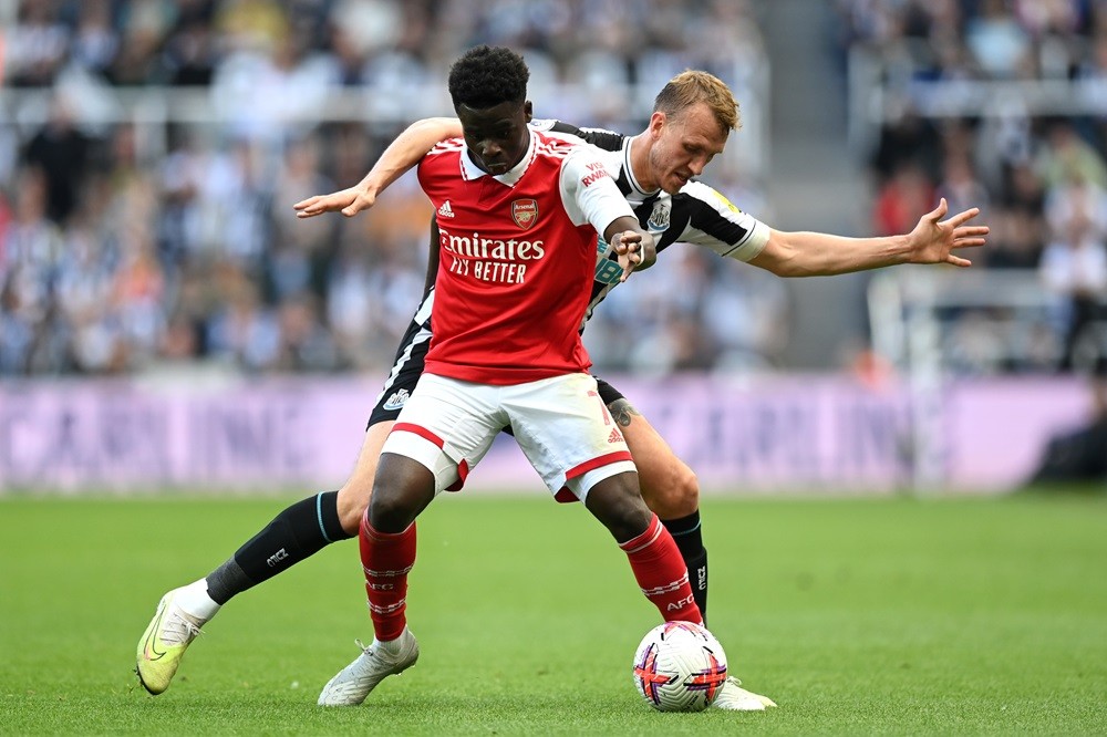 NEWCASTLE UPON TYNE, ENGLAND: Bukayo Saka of Arsenal is challenged by Dan Burn of Newcastle United during the Premier League match between Newcastl...