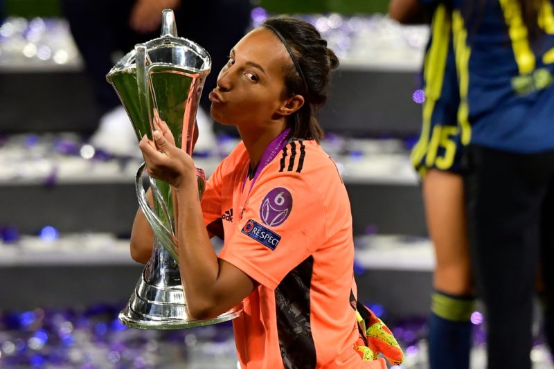 Lyon's French goalkeeper Sarah Bouhaddi kisses the winner's trophy as she celebrates with teammates after winning the UEFA Women's Champions League...