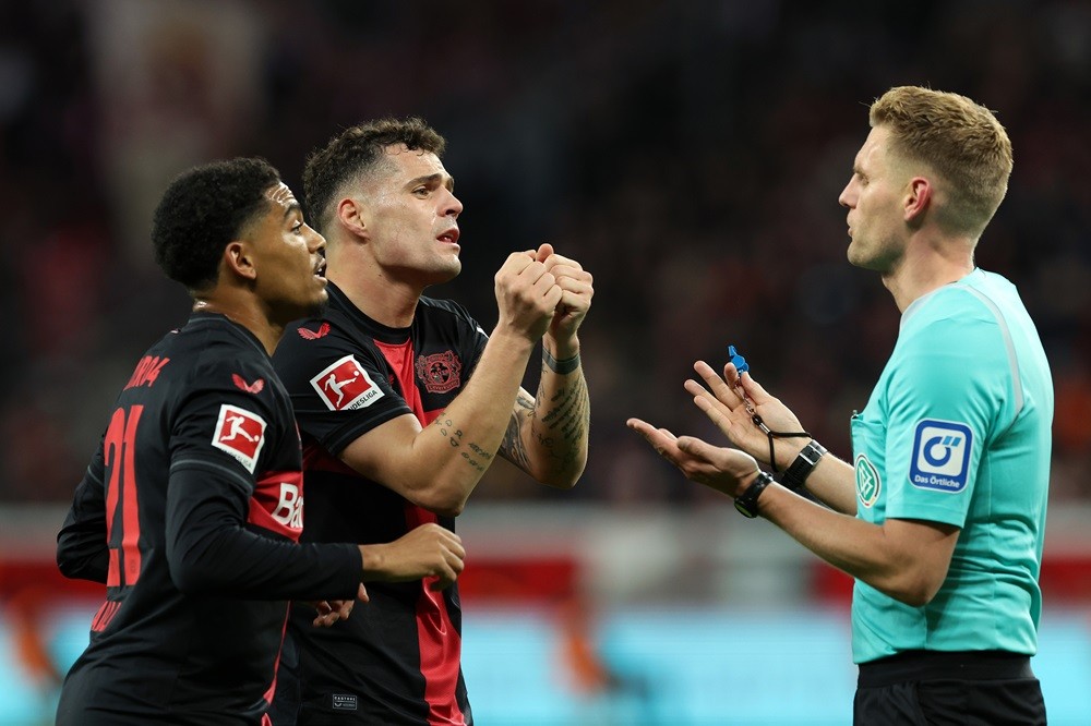 LEVERKUSEN, GERMANY: Amine Adli and Granit Xhaka of Bayer Leverkusen interact with Referee Timo Gerach during the Bundesliga match between Bayer 04 Leverkusen and 1. FSV Mainz 05 at BayArena on February 23, 2024. (Photo by Alexander Hassenstein/Getty Images)