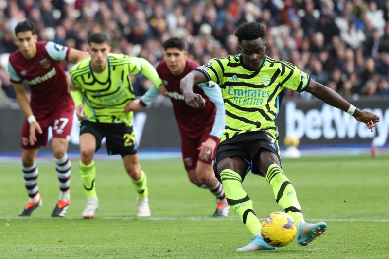 Arsenal's English midfielder #07 Bukayo Saka (R) scores their second goal from the penalty spot during the English Premier League football match be...