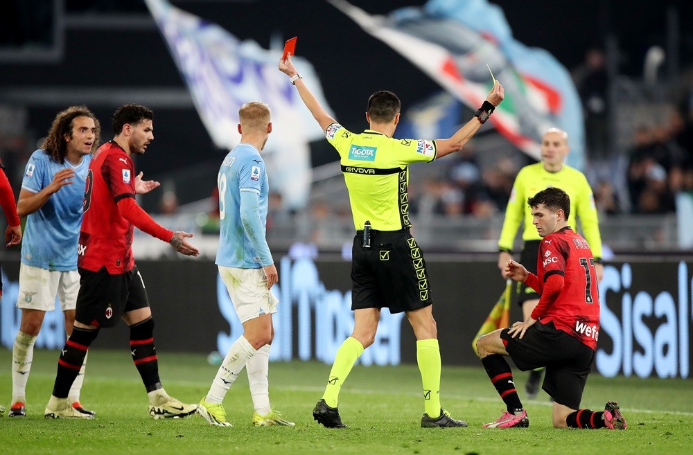 ROME, ITALY: Referee Marco Di Bello shows a red card to Matteo Guendouzi of SS Lazio as Christian Pulisic of AC Milan is shown a yellow card during...
