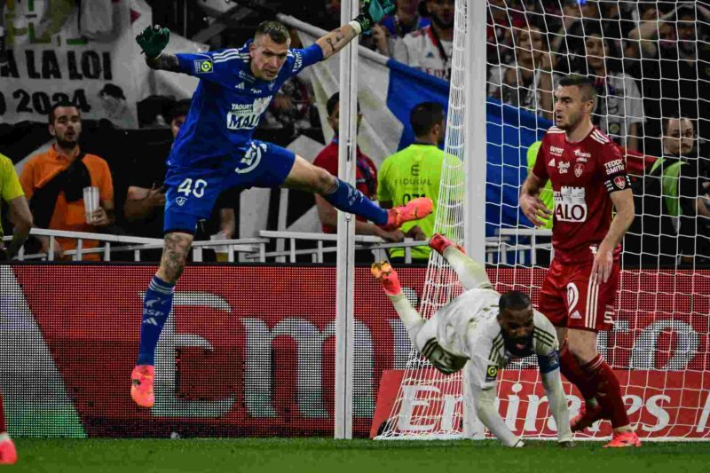 Lyon's French forward #10 Alexandre Lacazette (C) is fouled by Brest's Dutch goalkeeper #40 Marco Bizot (L) during the French L1 football match bee...