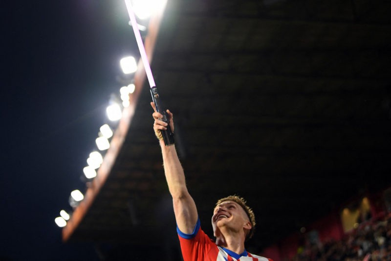 Viktor Tsygankov in a Girona FC jersey, holding up a lightsaber and smiling during a match.- Girona's Ukrainian forward #08 Viktor Tsygankov celebr...
