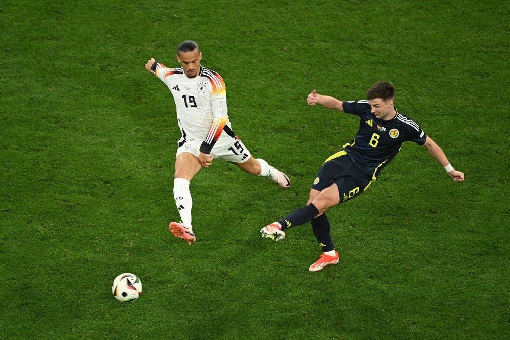 MUNICH, GERMANY: Kieran Tierney of Scotland passes the ball whilst under pressure from Leroy Sane of Germany during the UEFA EURO 2024 group stage match between Germany and Scotland at Munich Football Arena on June 14, 2024. (Photo by Clive Mason/Getty Images)