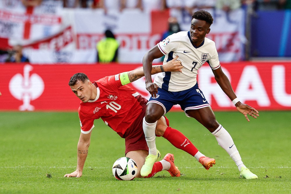 Switzerland's Granit Xhaka fights for the ball with England's Bukayo Saka during the UEFA Euro 2024 quarter-final football match between England an...