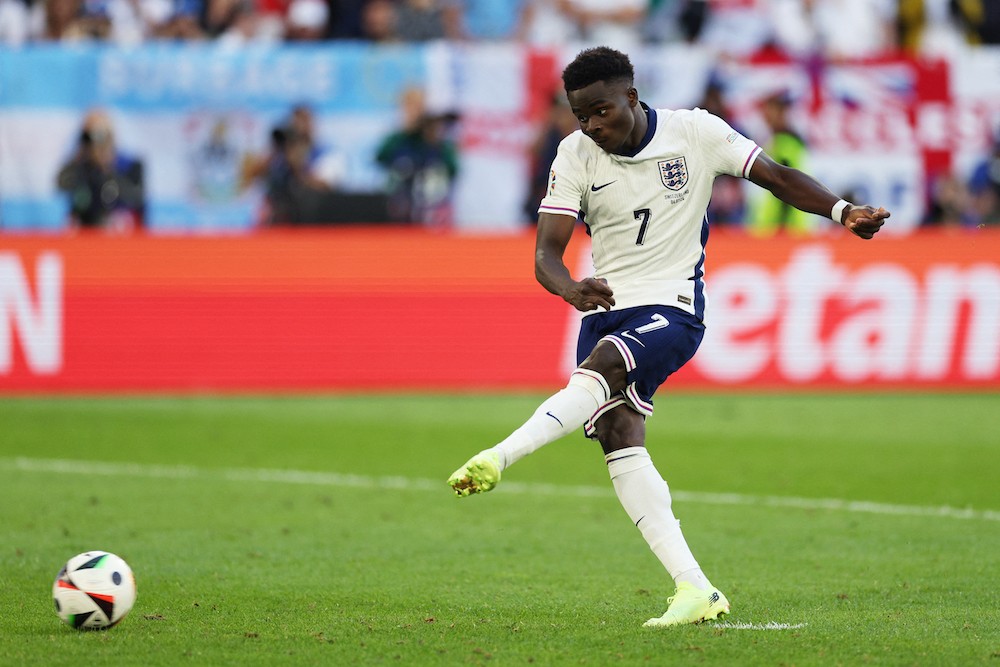 England's Bukayo Saka kicks the ball and scores during the penalty shootout at the end of the UEFA Euro 2024 quarter-final football match between E...