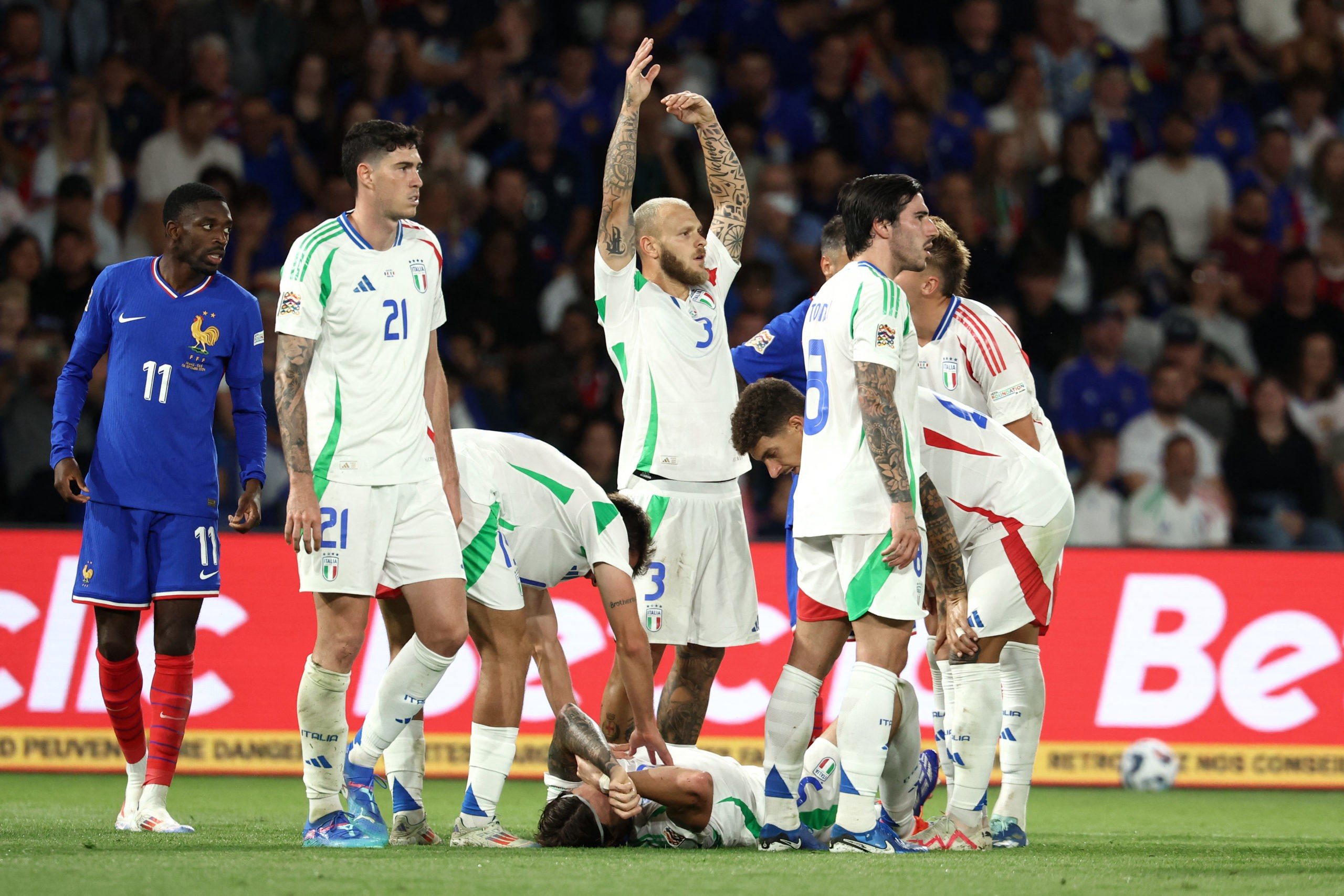 Italy's defender #03 Federico Dimarco (C) gestures as Italy's defender #05 Riccardo Calafiori lies on the football pitch during the UEFA Nations Le...