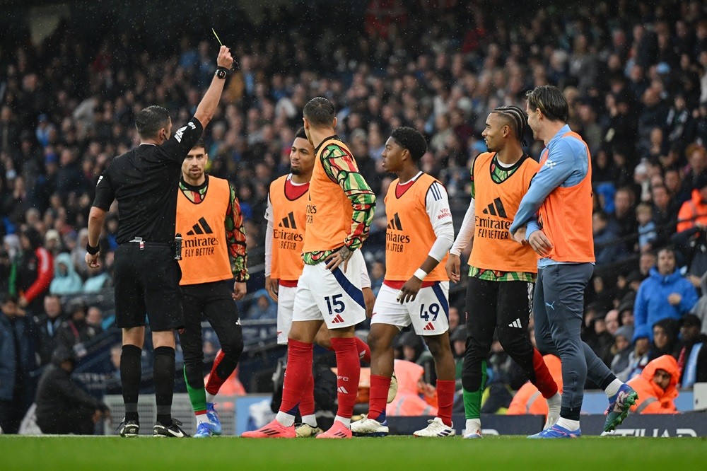 MANCHESTER, ENGLAND: Referee, Michael Oliver shows a yellow card to Myles Lewis-Skelly of Arsenal during the Premier League match between Mancheste...