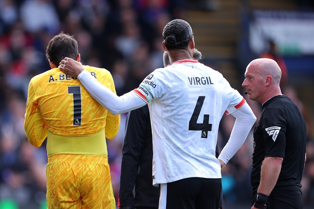 LONDON, ENGLAND: Virgil Van Dijk supports an injured Alisson Becker of Liverpool before leaving the pitch during the Premier League match between C...