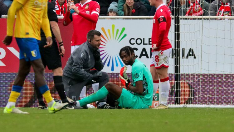 Arthur Okonkwo sits on the ground injured (Photo via WrexhamAFC.co.uk)