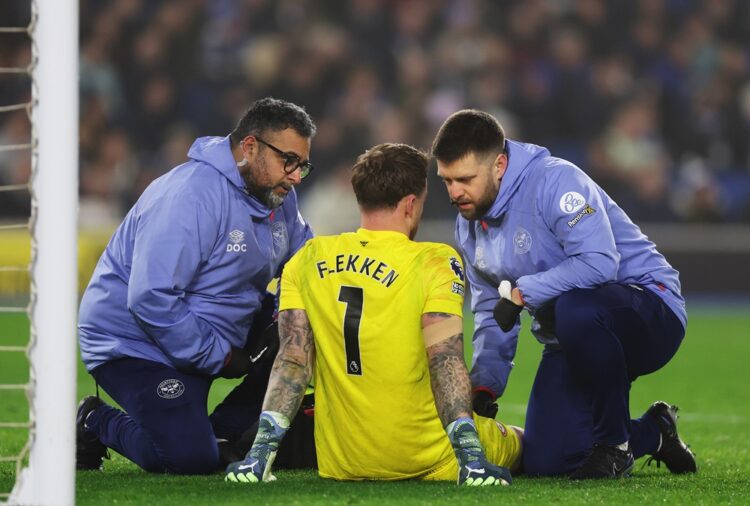 BRIGHTON, ENGLAND: Mark Flekken of Brentford receives medical treatment after he goes down with an injury during the Premier League match between B...