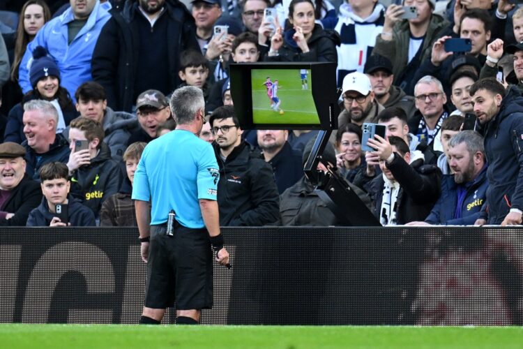 LONDON, ENGLAND: Referee Darren Bond checks the VAR screen before showing a red card to Tom Cairney of Fulham (not pictured) for a foul on Dejan Ku...