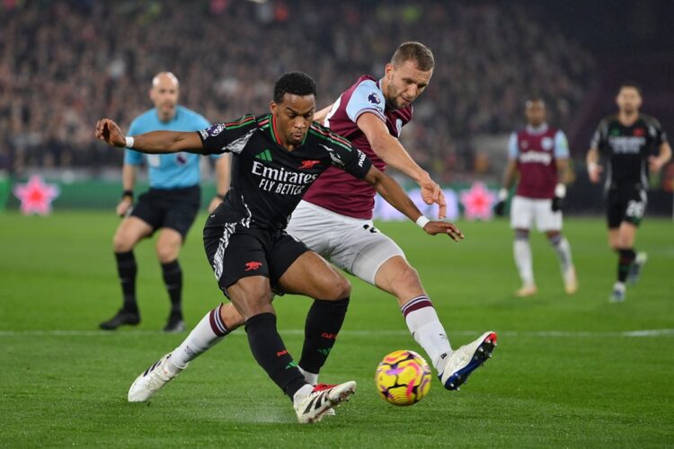 LONDON, ENGLAND: Jurrien Timber of Arsenal crosses the ball under pressure from Tomas Soucek of West Ham United during the Premier League match bet...