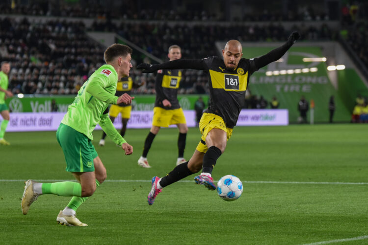 WOLFSBURG, GERMANY - DECEMBER 22: Donyell Malen of Borussia Dortmund in action pressured by Kilian Fischer of VfL Wolfsburg during the Bundesliga m...
