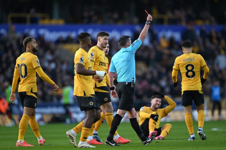 WOLVERHAMPTON, ENGLAND: Referee Michael Oliver shows a red card to Myles Lewis-Skelly of Arsenal (not pictured) after he fouled Matt Doherty of Wol...
