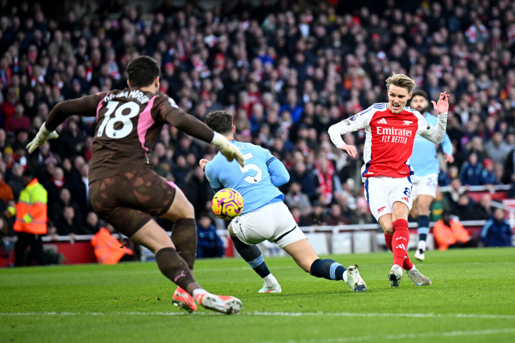 LONDON, ENGLAND - FEBRUARY 02: Martin Odegaard of Arsenal scores his team's first goal whilst under pressure from John Stones of Manchester City as Stefan Ortega of Manchester City fails to make a save during the Premier League match between Arsenal FC and Manchester City FC at Emirates Stadium on February 02, 2025 in London, England. (Photo by Justin Setterfield/Getty Images)