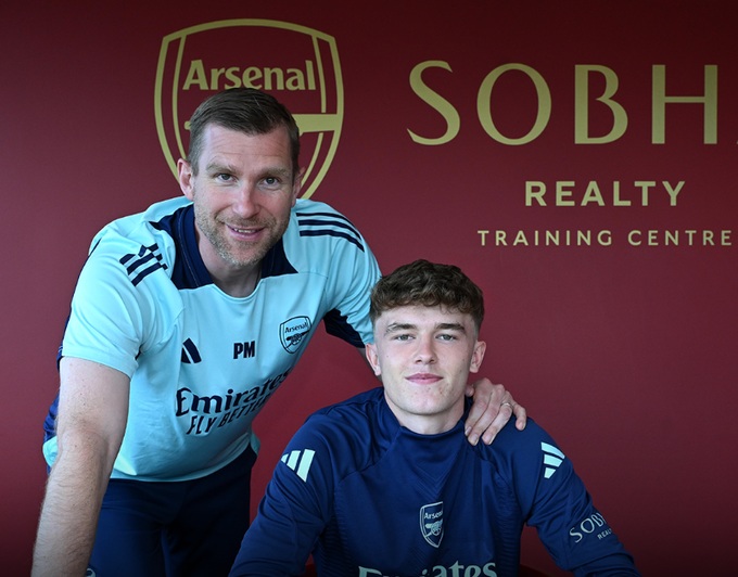 Ceadach O'Neill alongside Per Mertesacker, signing his first professional contract with Arsenal (Photo via Arsenal.com)