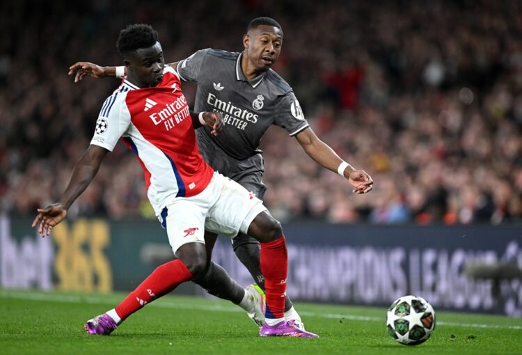 LONDON, ENGLAND: David Alaba of Real Madrid is tackled by Bukayo Saka of Arsenal during the UEFA Champions League 2024/25 Quarter Final First Leg m...