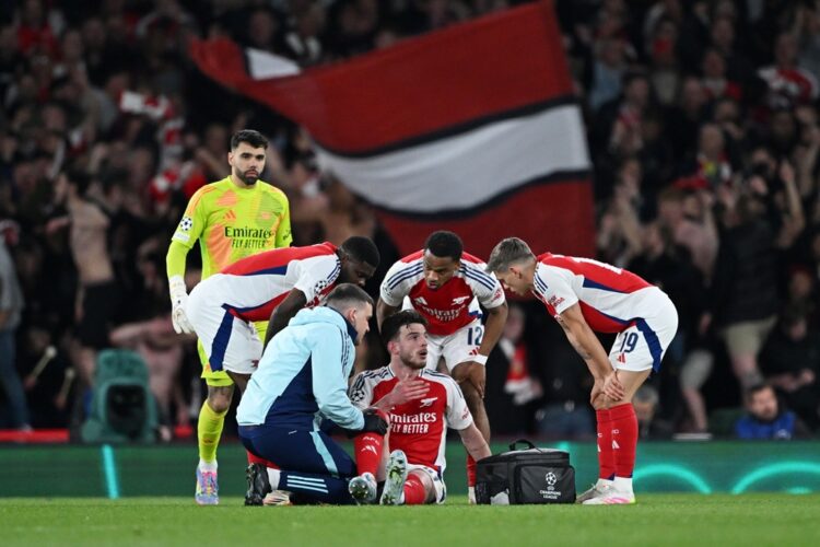 LONDON, ENGLAND: Declan Rice of Arsenal speaks to team mates Thomas Partey, Jurrien Timber and Leandro Trossard as he is treated by Simon Murphy, P...