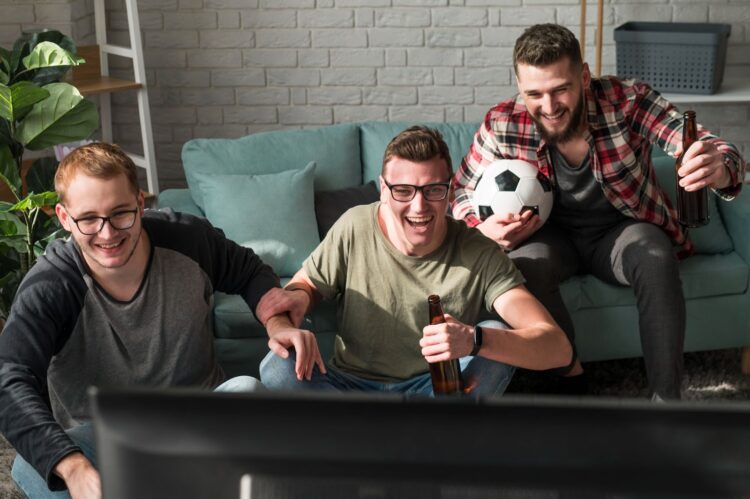 three men watching football on tv betting