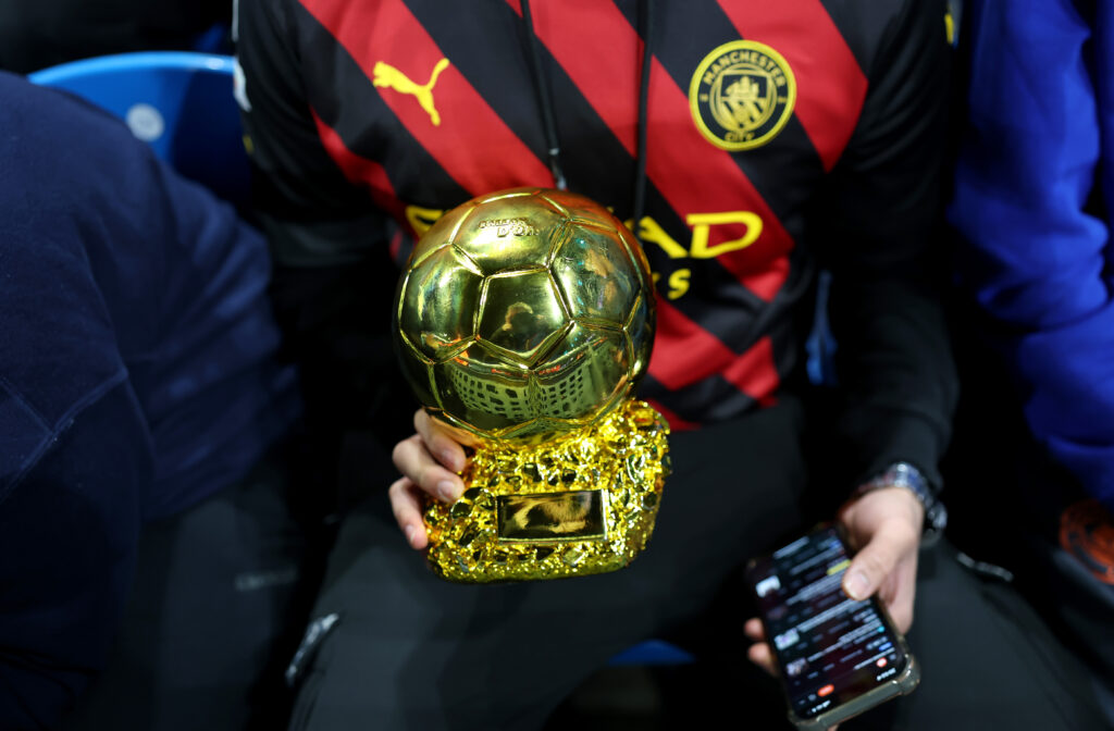MANCHESTER, ENGLAND - FEBRUARY 11: A Manchester City fan is seen with a replica Ballon d'Or trophy in the stands during the UEFA Champions League 2024/25 League Knockout Play-off first leg match between Manchester City and Real Madrid C.F. at Manchester City Stadium on February 11, 2025 in Manchester, England. (Photo by Carl Recine/Getty Images)