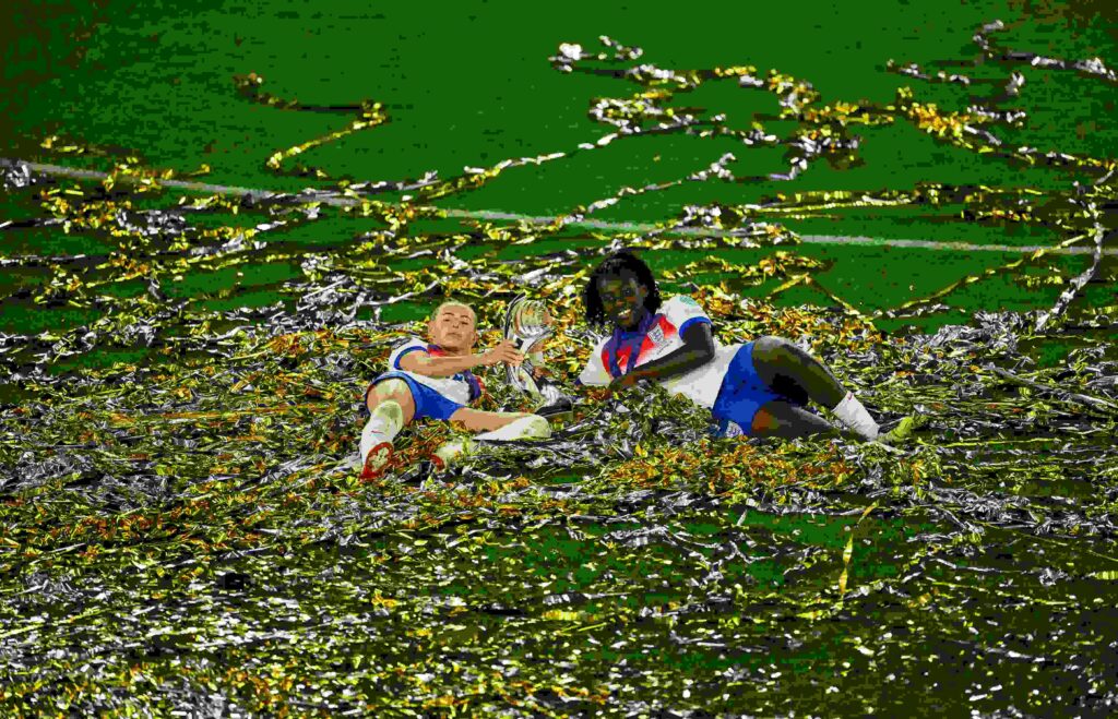 Chloe Kelly and Michelle Agyemang of England celebrate with the UEFA Women's EURO trophy while laying in ticker tape after their team's victory in ...