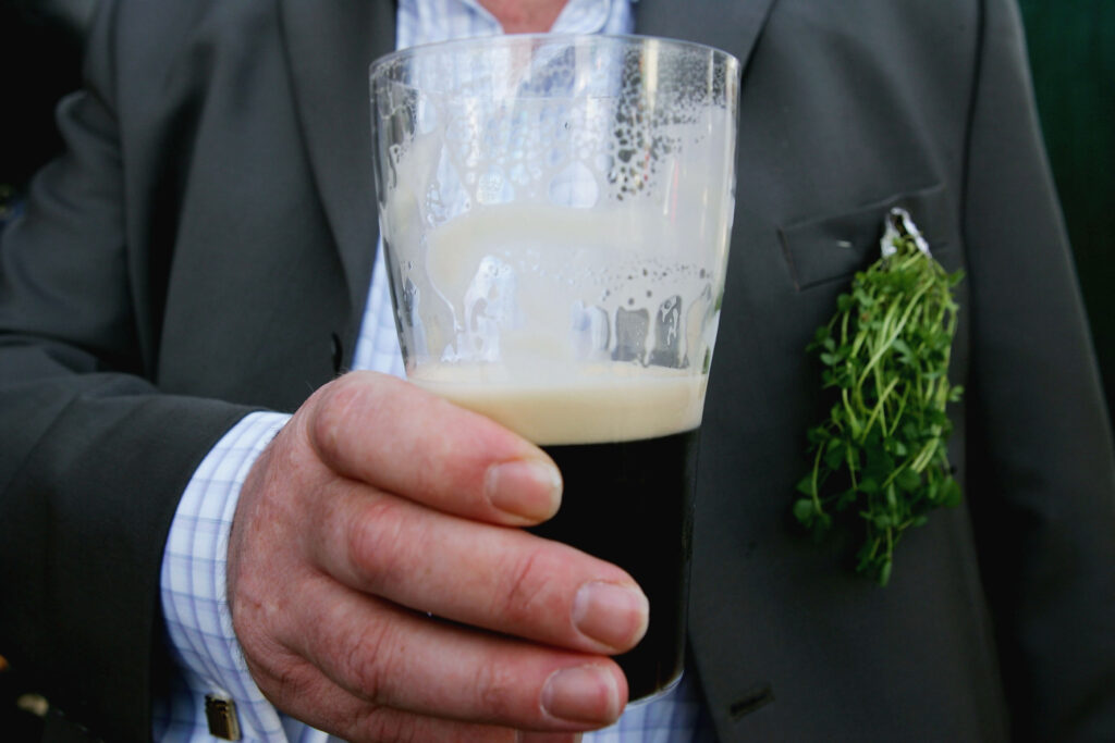 CHELTENHAM, ENGLAND - MARCH 17: A shamrock bedecked racegoer enjoys a pint of Guinness on St Patricks Day, at Cheltenham Racecourse during the third day of the annual National Hunt Festival on March 17, 2005 in Cheltenham, England. (Photo by Julian Herbert/Getty Images)