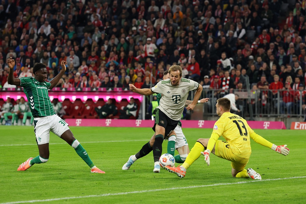 MUNICH, GERMANY: Harry Kane of Bayern Munich takes a shot whilst under pressure from Karl Hein of Werder Bremen during the Bundesliga match between FC Bayern München and SV Werder Bremen at Allianz Arena on September 26, 2025. (Photo by Alexander Hassenstein/Getty Images)