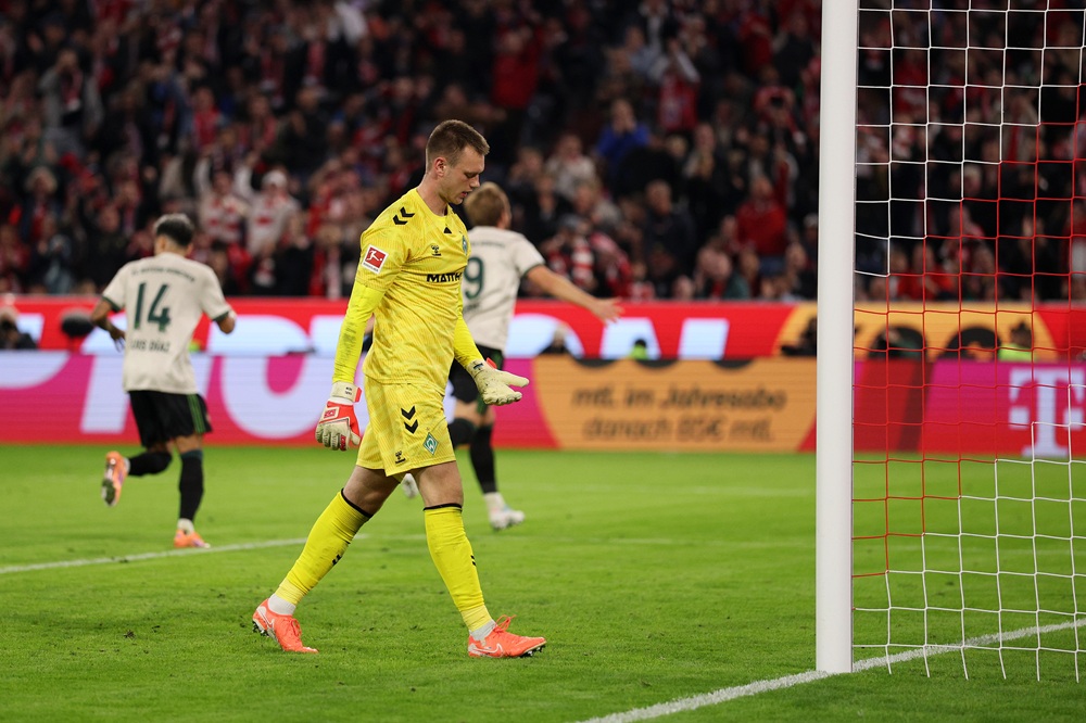 MUNICH, GERMANY: Karl Hein of Werder Bremen looks dejected as Harry Kane of Bayern Munich (obscured) celebrates scoring his team's third goal to reach a record 100 club goals during the Bundesliga match between FC Bayern München and SV Werder Bremen at Allianz Arena on September 26, 2025. (Photo by Adam Pretty/Getty Images)