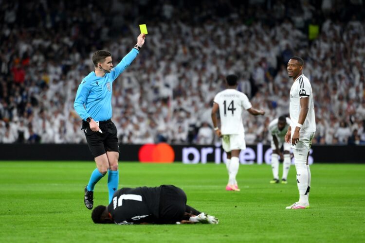 MADRID, SPAIN: Referee Francois Letexier shows a yellow card to David Alaba of Real Madrid for a foul on Bukayo Saka of Arsenal during the UEFA Cha...