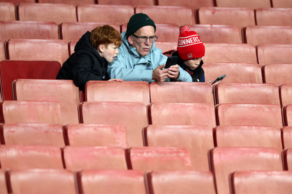 LONDON, ENGLAND - OCTOBER 29: Fans of Arsenal look at their mobile phones as they take their seats on the inside of the stadium prior to the Carabao Cup Fourth Round match between Arsenal and Brighton & Hove Albion at Emirates Stadium on October 29, 2025 in London, England. (Photo by Eddie Keogh/Getty Images)