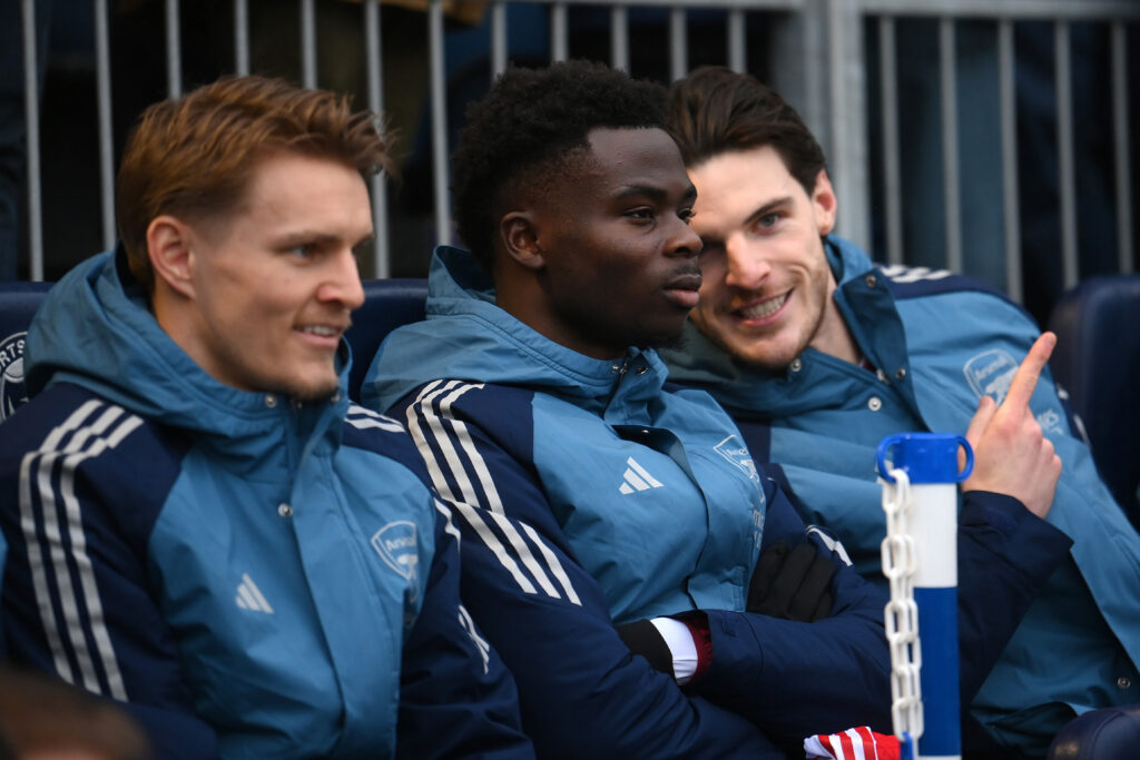 PORTSMOUTH, ENGLAND - JANUARY 11: Declan Rice of Arsenal (R) talks with Bukayo Saka of Arsenal on the substitute's bench ahead of the Emirates FA Cup Third Round match between Portsmouth and Arsenal on January 11, 2026 in Portsmouth, England. (Photo by Mike Hewitt/Getty Images)