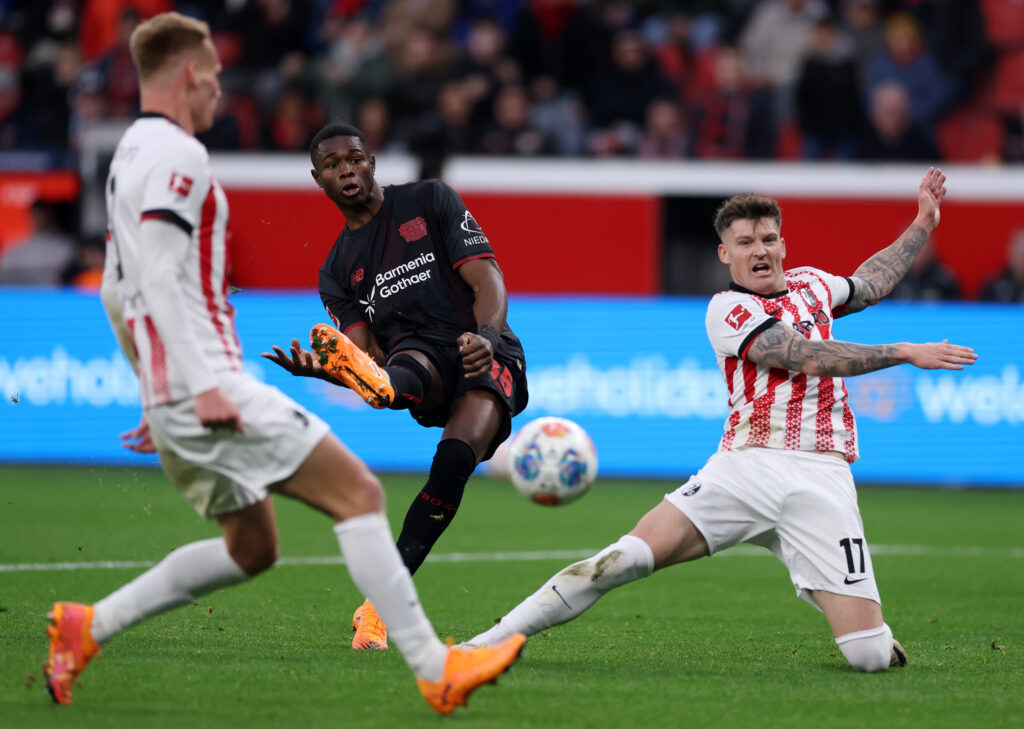 LEVERKUSEN, GERMANY - OCTOBER 26: Christian Kofane of Bayer Leverkusen shoots whilst under pressure from Lukas Kubler of SC Freiburg during the Bundesliga match between Bayer 04 Leverkusen and SC Freiburg at BayArena on October 26, 2025 in Leverkusen, Germany. (Photo by Dean Mouhtaropoulos/Getty Images)