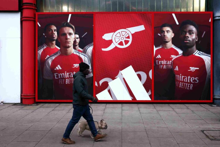 LONDON, ENGLAND - JANUARY 18: A man walks his dog outside the stadium in-front of an Adidas advert featuring Martin Odegaard and Bukayo Saka prior ...